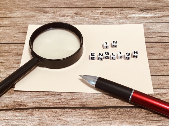 in Englishと記載のある紙と虫眼鏡とペン